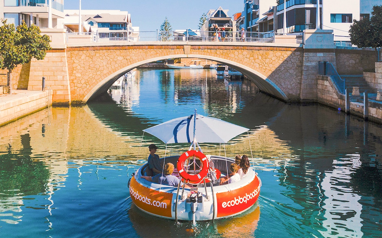 Group enjoying a self-drive BBQ boat under a bridge in Mandurah.