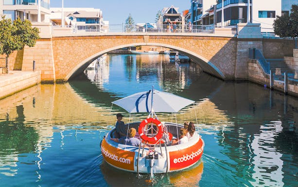 Group enjoying a self-drive BBQ boat under a bridge in Mandurah.
