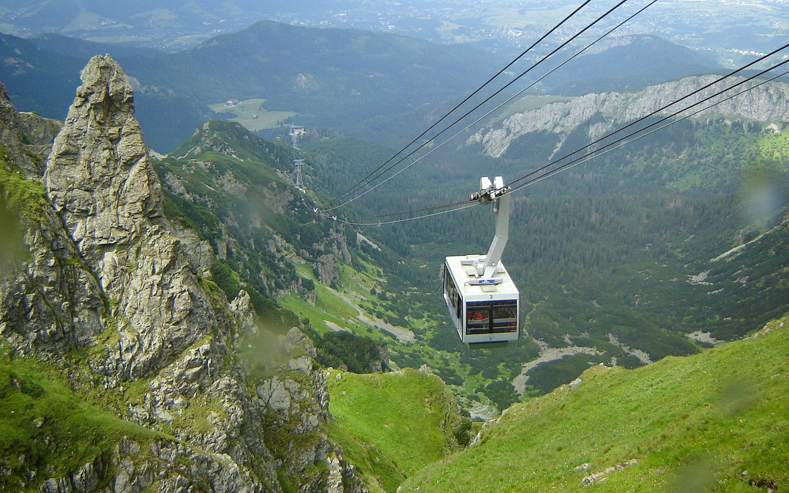 Cable car ascending over green mountains in Zakopane, Poland.
