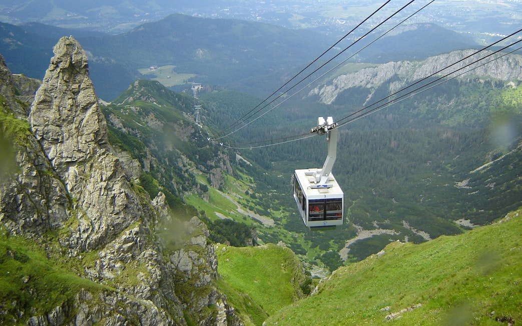 Cable car ascending over green mountains in Zakopane, Poland.