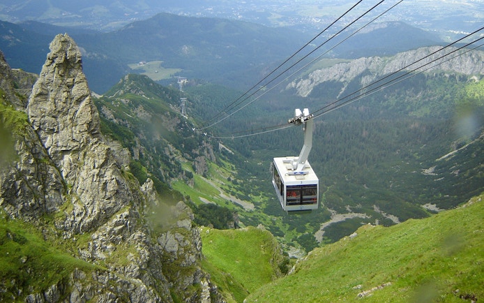 Cable car ascending over green mountains in Zakopane, Poland.