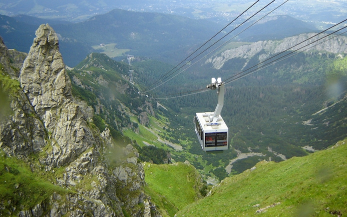 Cable car ascending over green mountains in Zakopane, Poland.