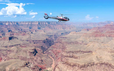 Helicopter flying over Grand Canyon South Rim with expansive canyon views.