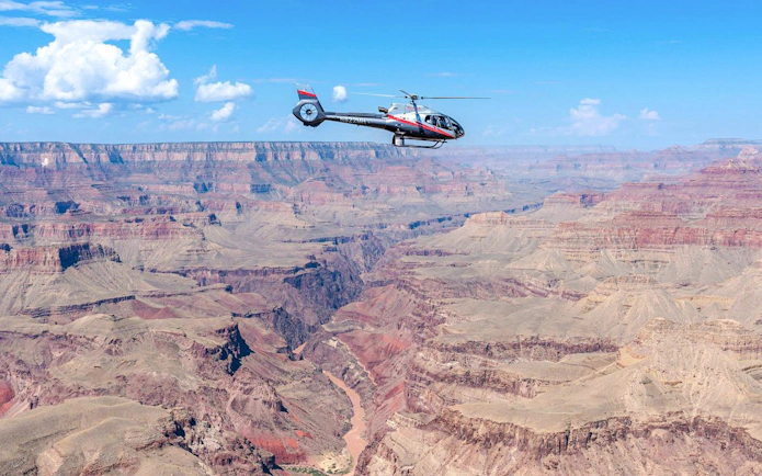 Helicopter flying over Grand Canyon South Rim with expansive canyon views.