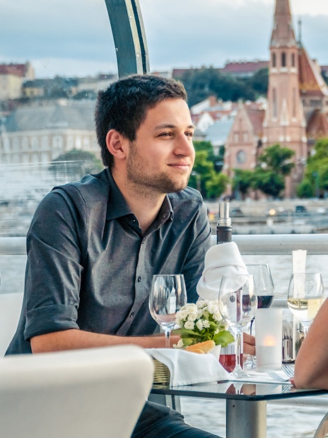 Couple enjoying a candlelit dinner on a Budapest river cruise with cityscape views.