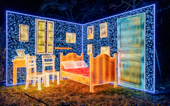 Lumina Park Wonderworld installation featuring illuminated bedroom scene with bed and chairs.