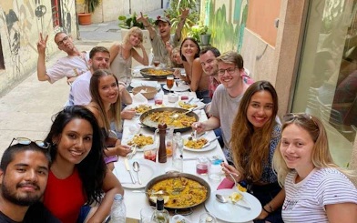 Group enjoying paella at outdoor table during Valencia cooking class.