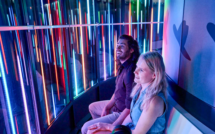 Visitors enjoying the colorful light display inside the Euroscoop at Euromast Lookout.