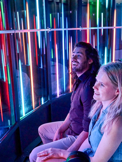 Visitors enjoying the colorful light display inside the Euroscoop at Euromast Lookout.
