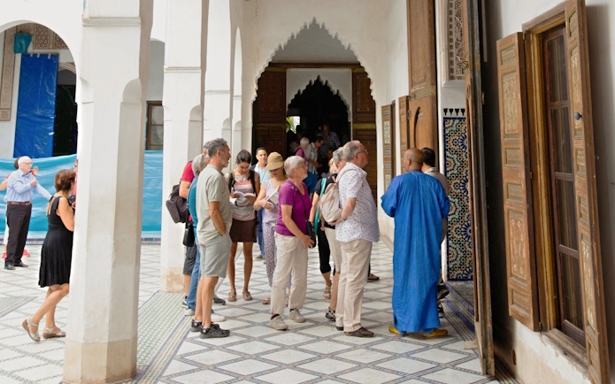 Tourists exploring Ben Youssef Medersa courtyard, Marrakech.