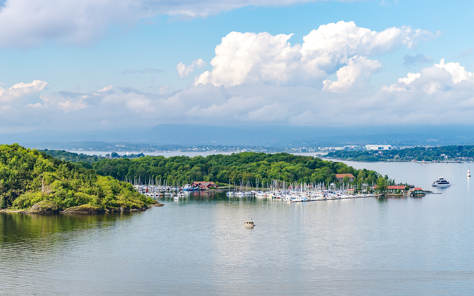 Hovedoya Island marina with boats and lush greenery in Oslofjord, Norway.