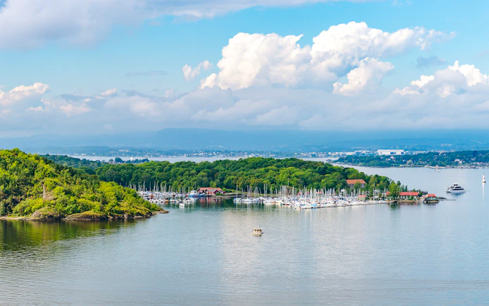 Hovedoya Island marina with boats and lush greenery in Oslofjord, Norway.