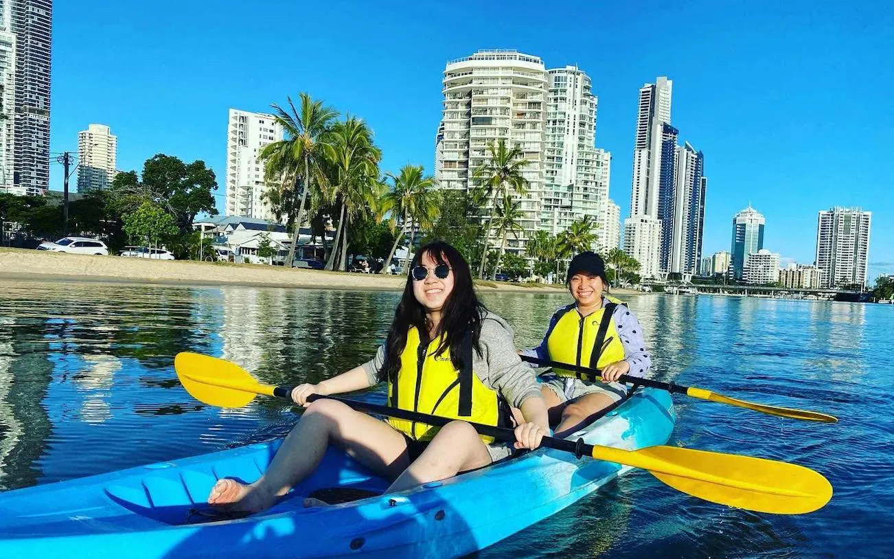 Kayakers paddling on Gold Coast waters with city skyline in the background.