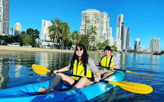 Kayakers paddling on Gold Coast waters with city skyline in the background.