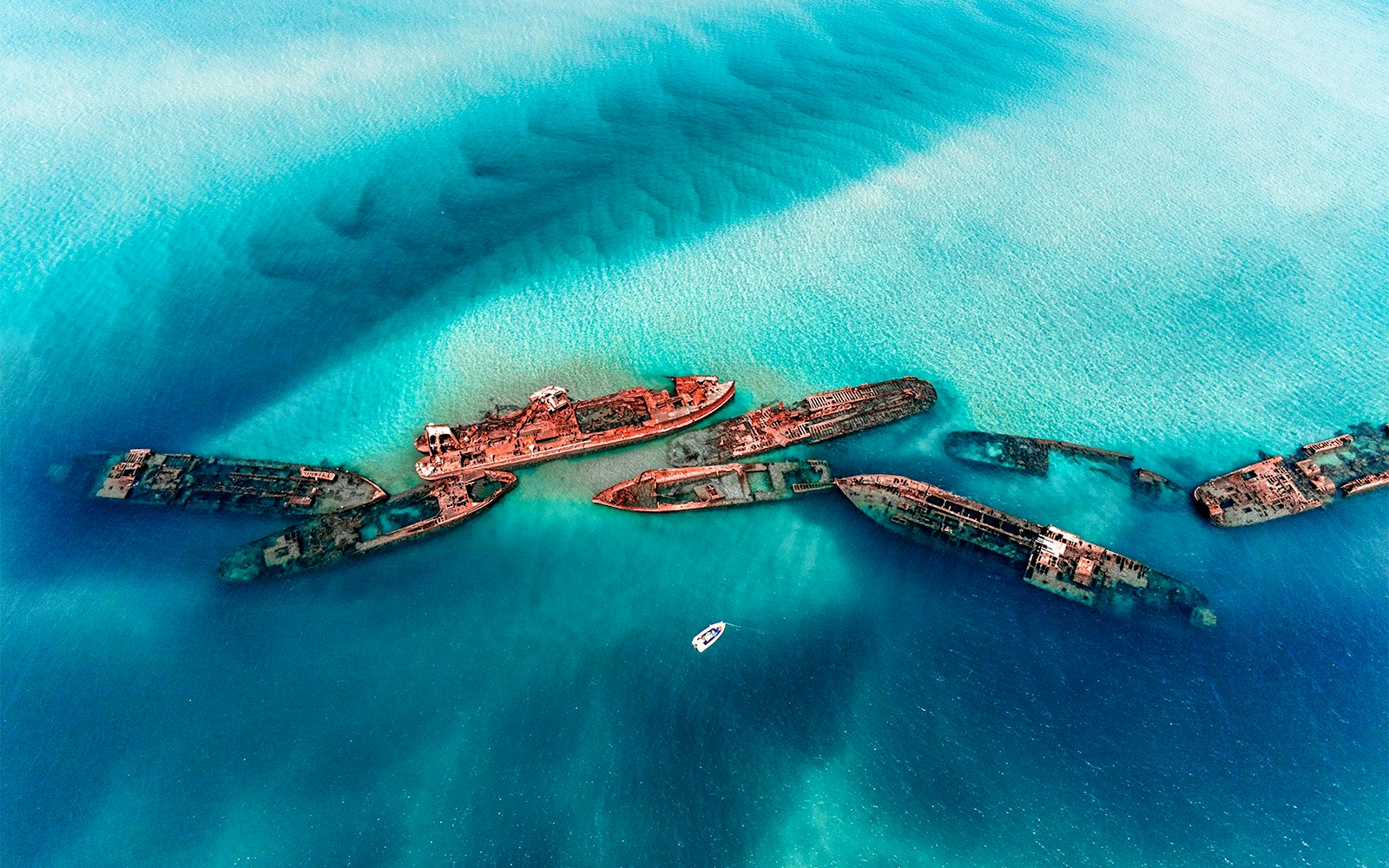 Tangalooma Wrecks at Moreton Island with a boat nearby in clear blue water.