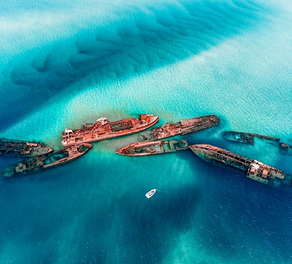Tangalooma Wrecks at Moreton Island with a boat nearby in clear blue water.