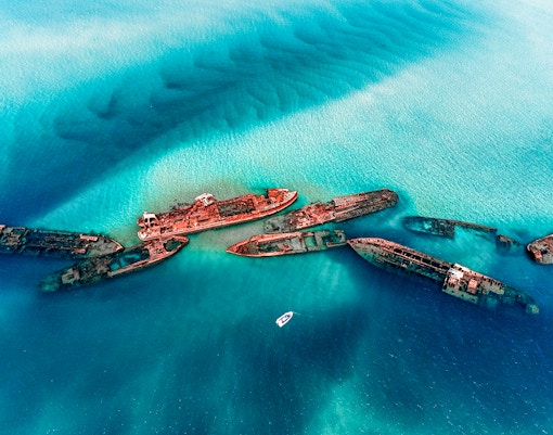 Tangalooma Wrecks at Moreton Island with a boat nearby in clear blue water.