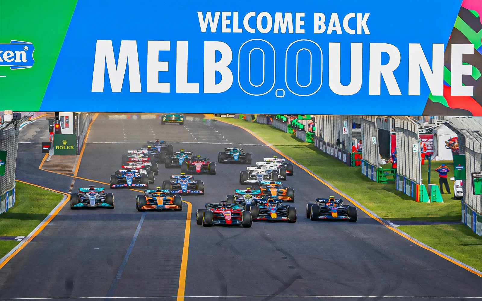Formula 1 cars racing under "Welcome Back Melbourne" sign at Australian Grand Prix 2023.
