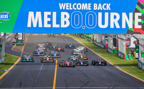 Formula 1 cars racing under "Welcome Back Melbourne" sign at Australian Grand Prix 2023.