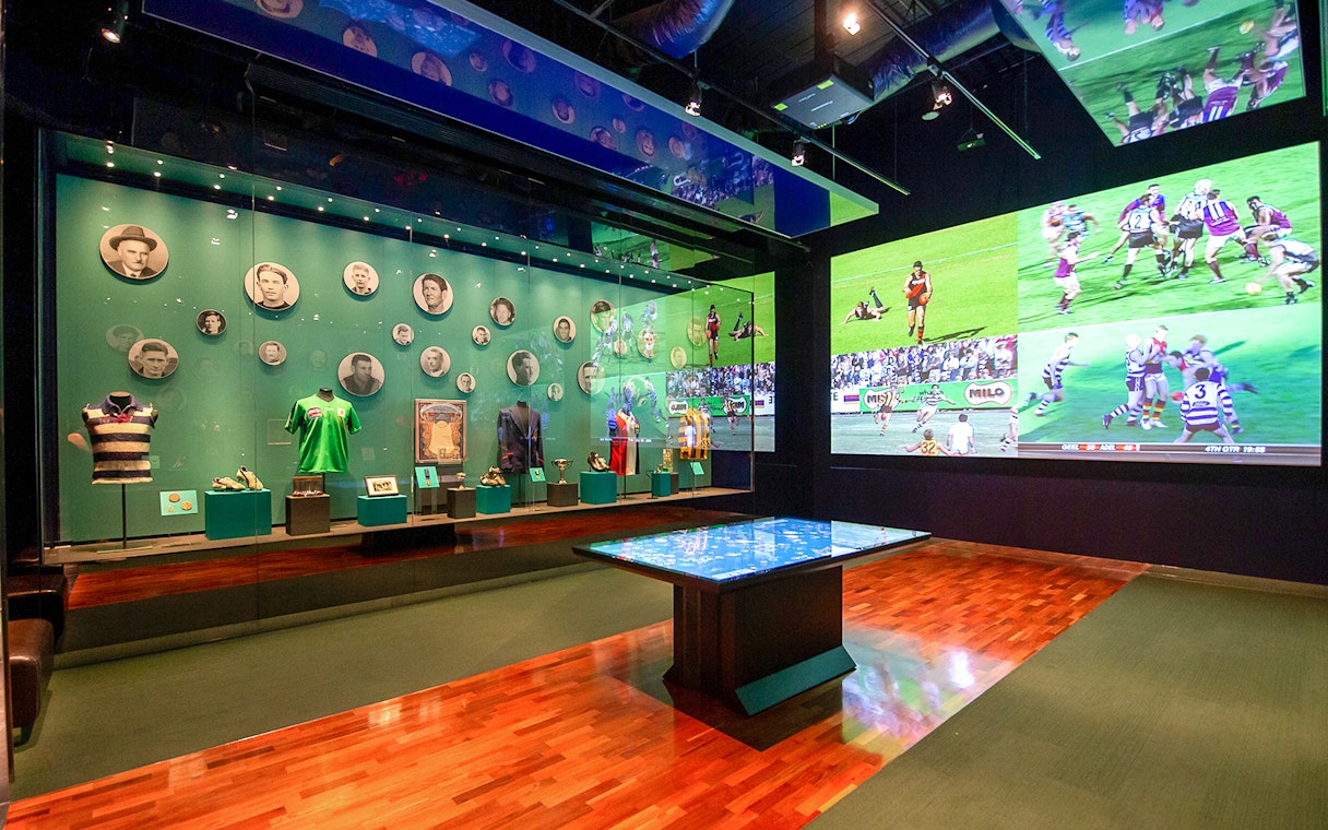 MCG sports memorabilia display with historic jerseys and player photos.