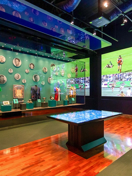 MCG sports memorabilia display with historic jerseys and player photos.