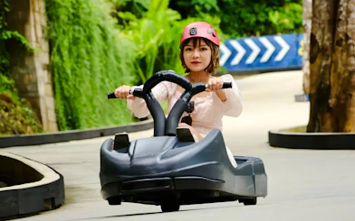 Young woman riding a luge at Hanuman Luge, surrounded by lush greenery.