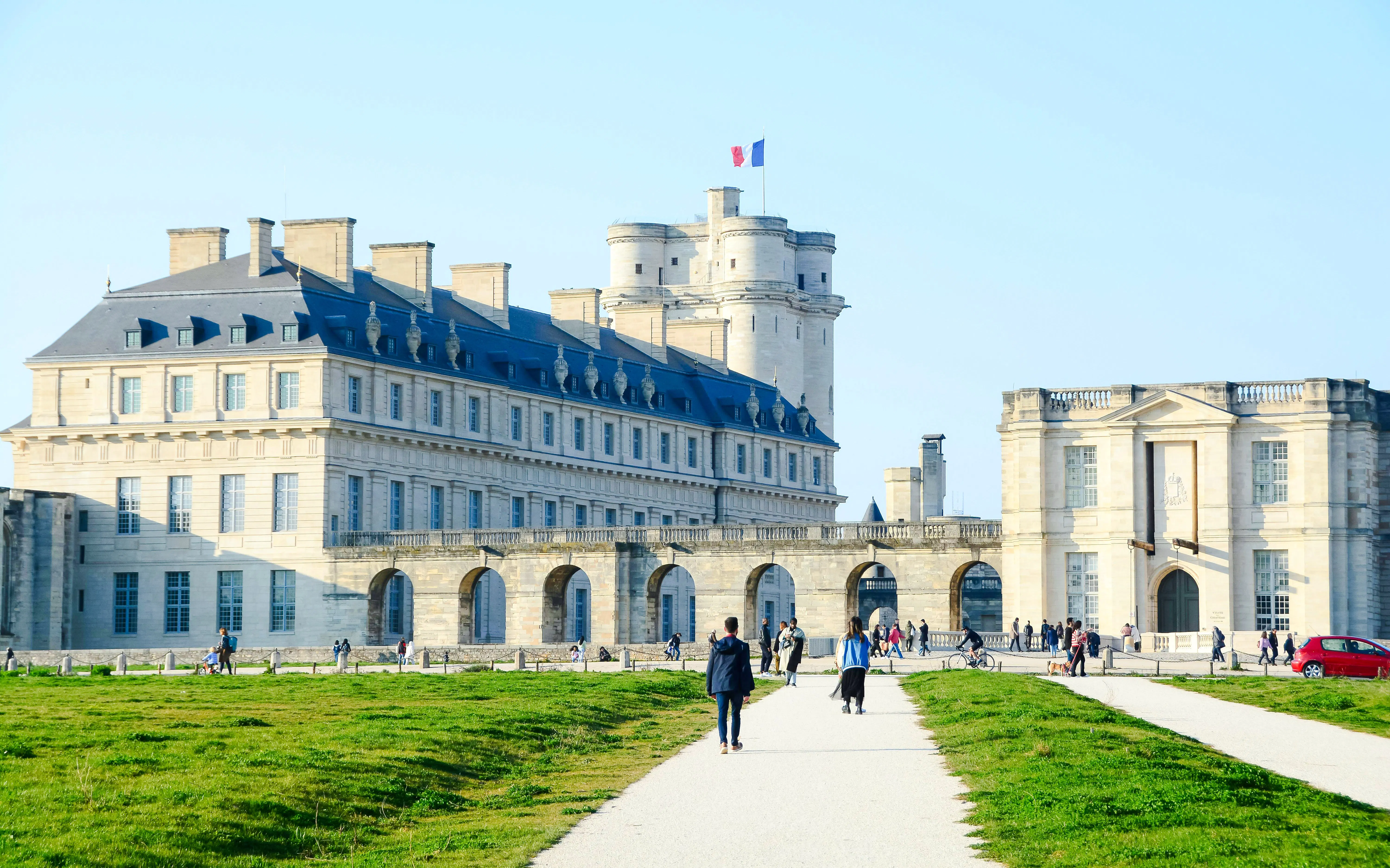 Vincennes Castle with visitors walking along the path in front of the historic fortress.