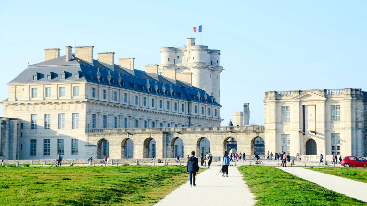 Vincennes Castle with visitors walking along the path in front of the historic fortress.