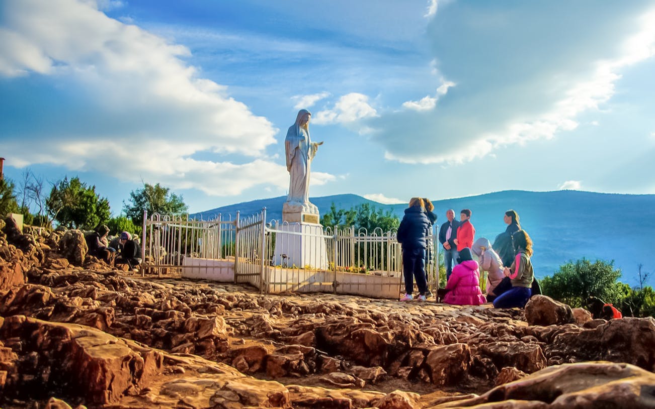 Pilgrims gather at the statue on Apparition Hill, Medjugorje, Bosnia and Herzegovina.