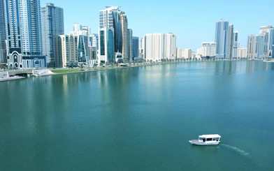 Boat cruising on Khalid Lagoon with Sharjah skyline in the background.