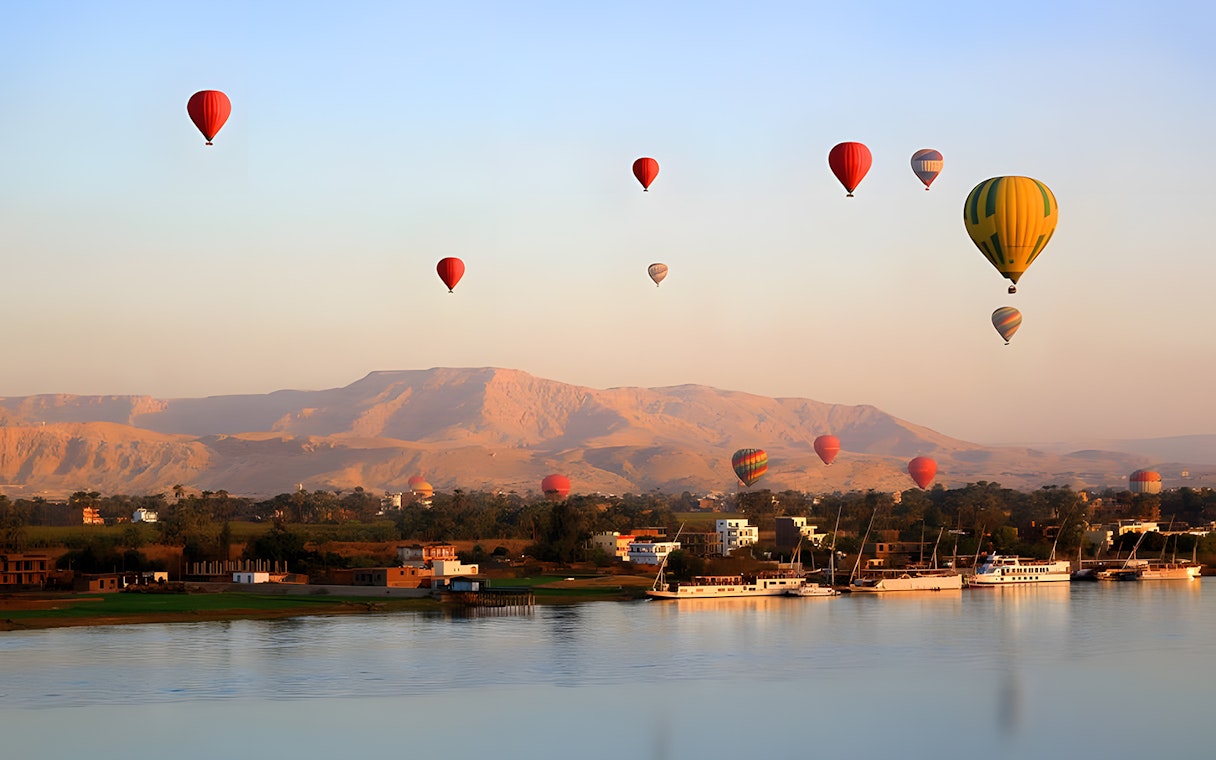 Hot air balloons over Nile River with mountains in Luxor, Egypt.