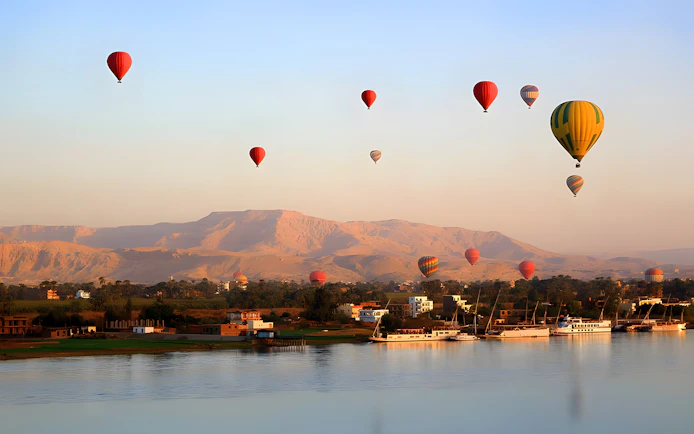 Hot air balloons over Nile River with mountains in Luxor, Egypt.
