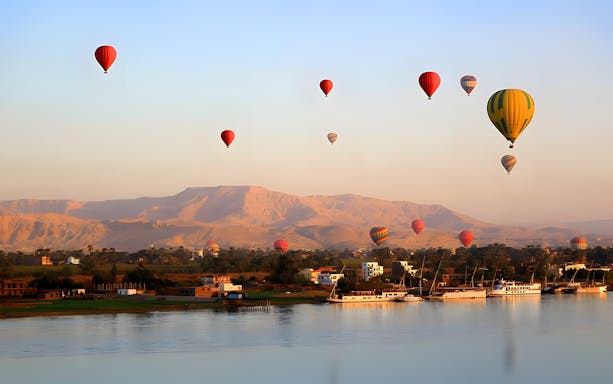 Hot air balloons over Nile River with mountains in Luxor, Egypt.