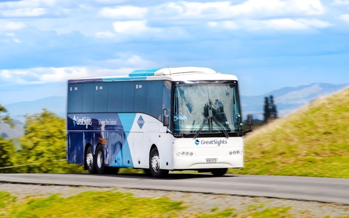 Bus on Hobbiton Movie Set Guided Tour in New Zealand countryside.