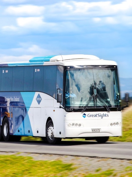 Bus on Hobbiton Movie Set Guided Tour in New Zealand countryside.
