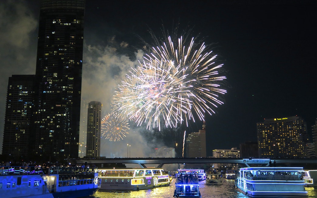 Fireworks over Chao Phraya River with cruise boats in Bangkok.