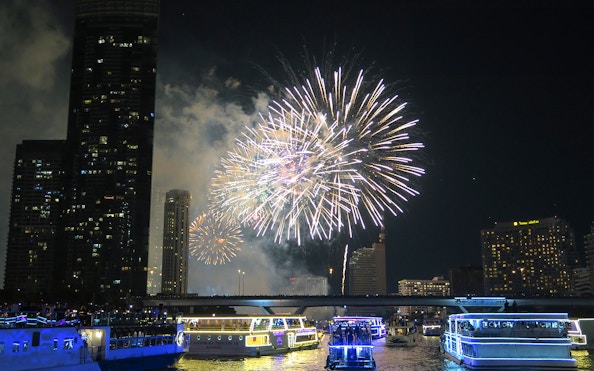 Fireworks over Chao Phraya River with cruise boats in Bangkok.