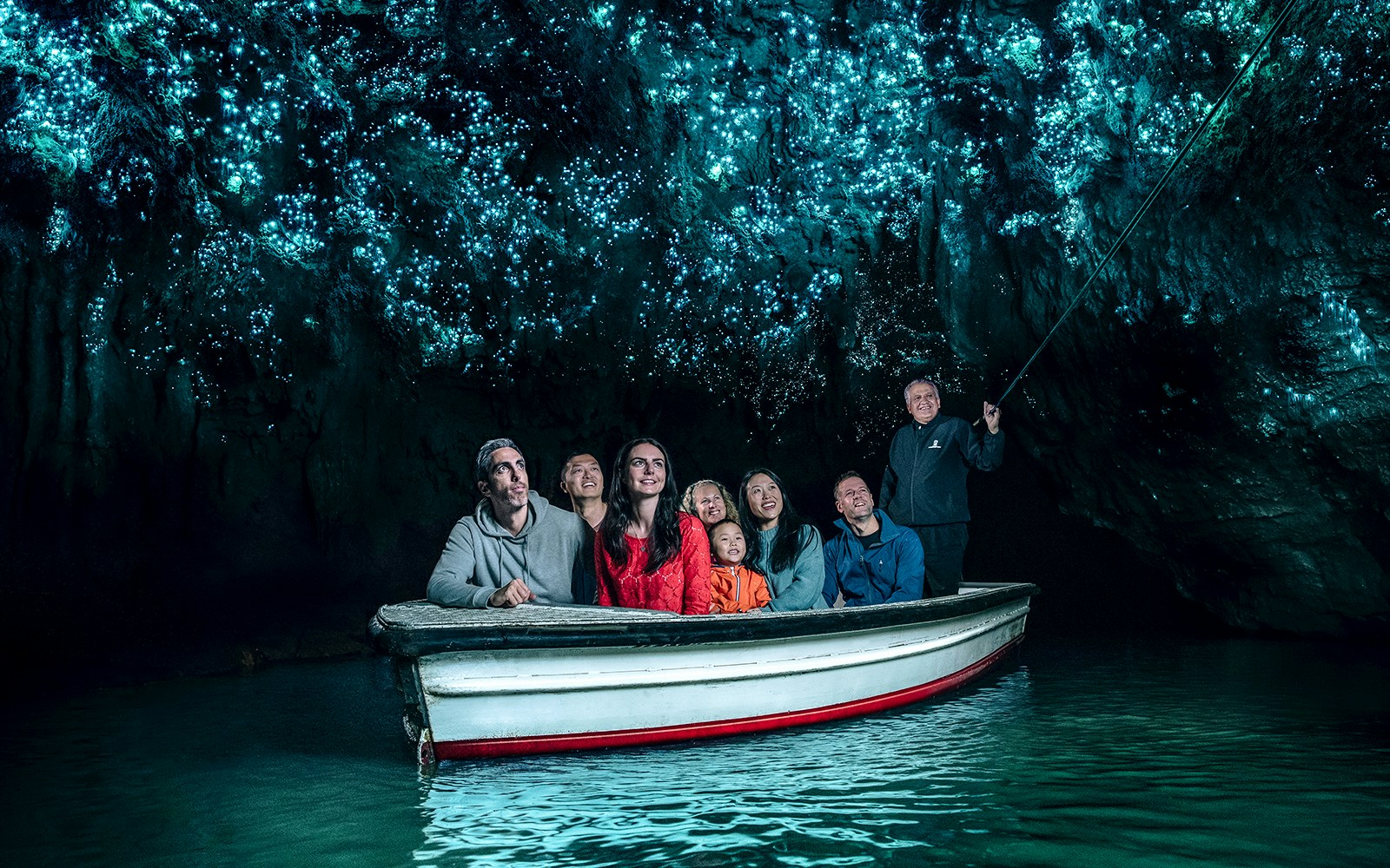 Group in boat under glowworms at Waitomo Caves, New Zealand.