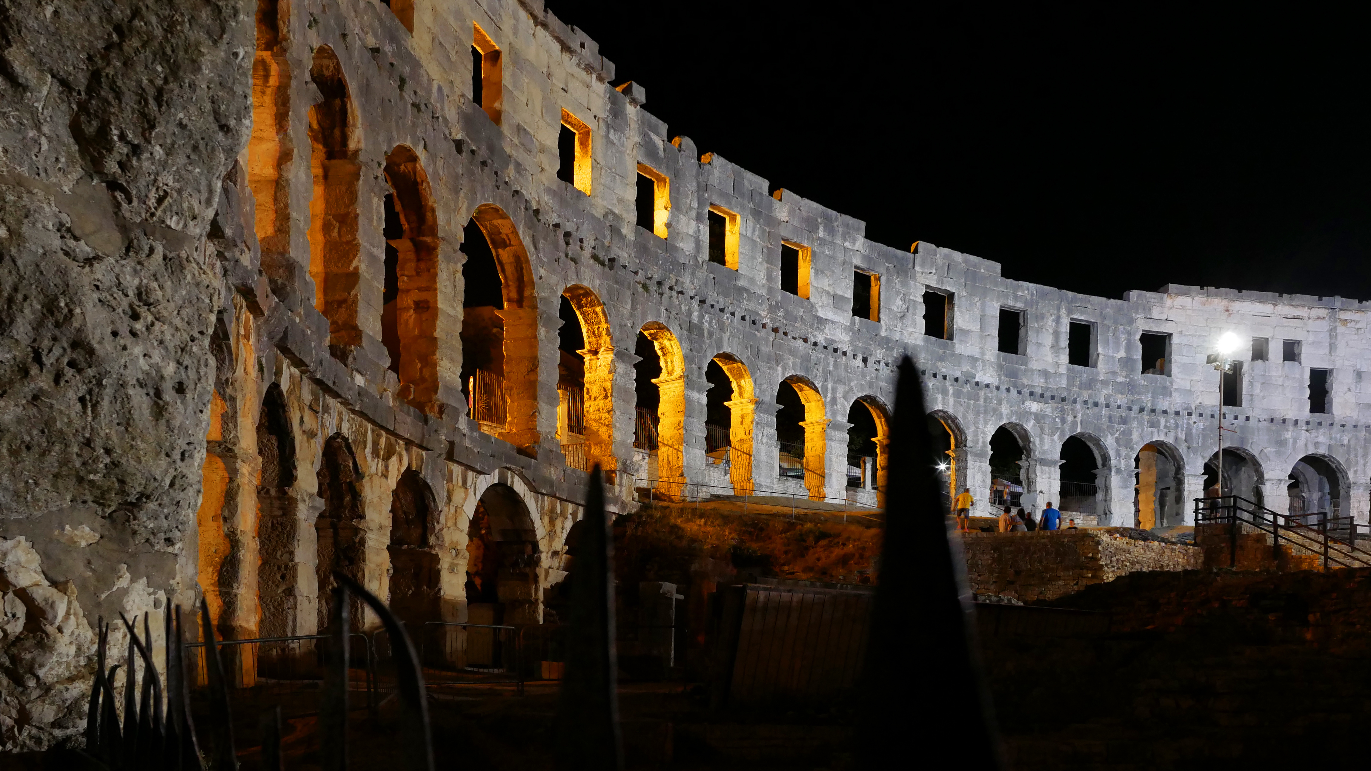 Colosseum illuminated at night with glowing arches in Rome, Italy.