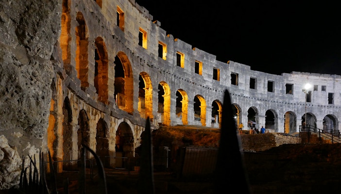 Colosseum illuminated at night with glowing arches in Rome, Italy.