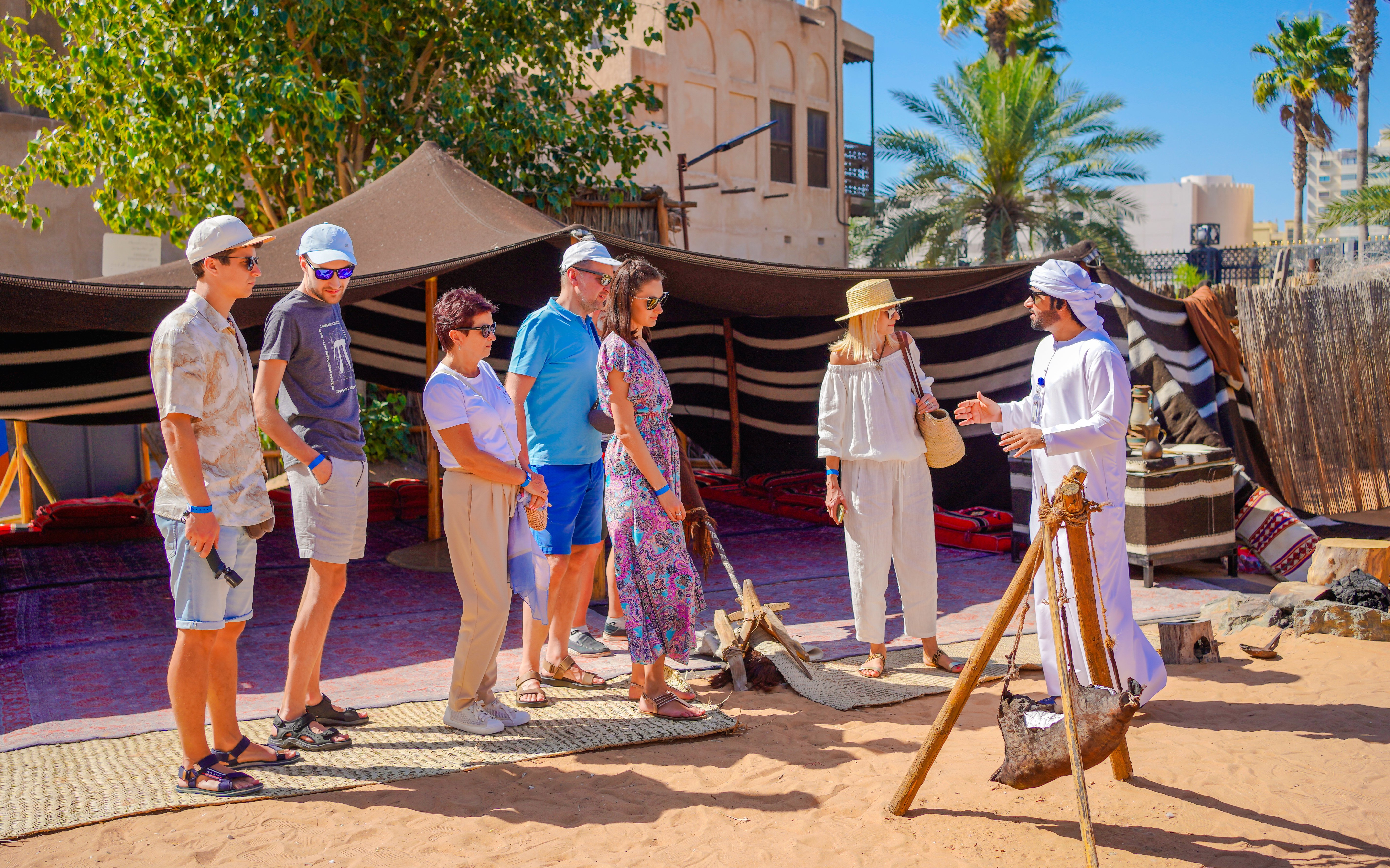 Guide interacting with tourists at a traditional desert camp in Dubai.