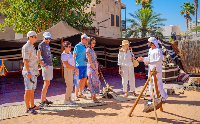 Guide interacting with tourists at a traditional desert camp in Dubai.