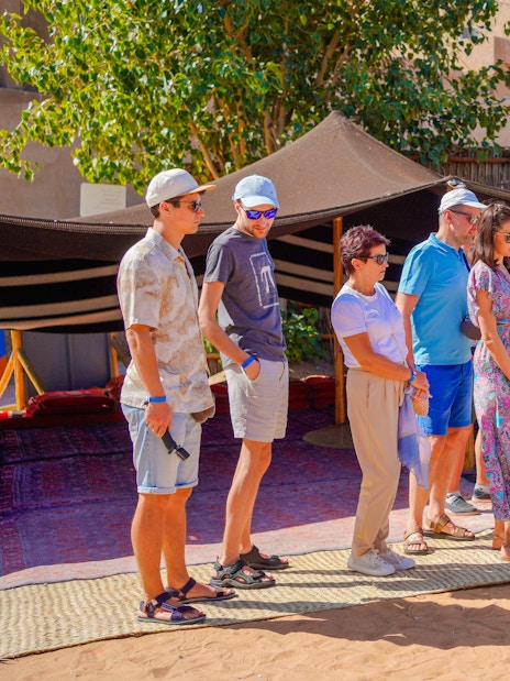 Guide interacting with tourists at a traditional desert camp in Dubai.