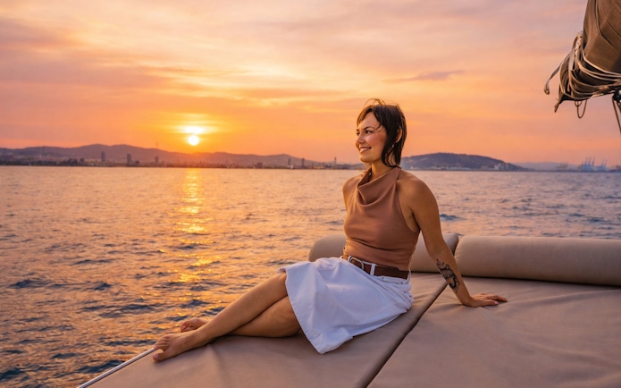Tourist relaxing on yacht at sunset in Barcelona.