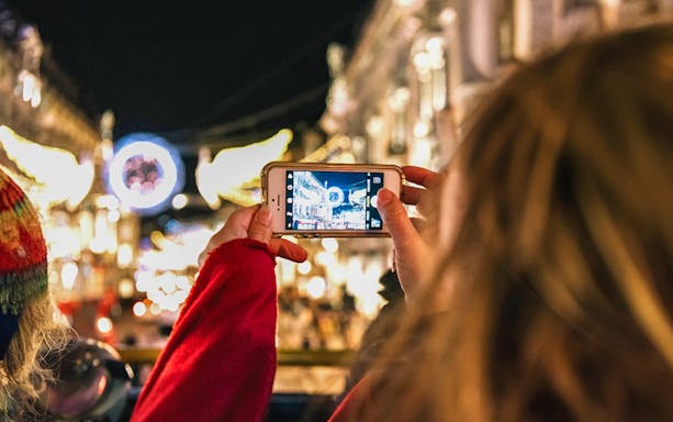 Person photographing London Christmas lights from Tootbus tour.