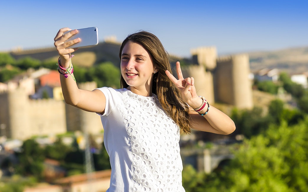 Person taking a selfie with Avila city walls in the background during Segovia & Avila day trip.