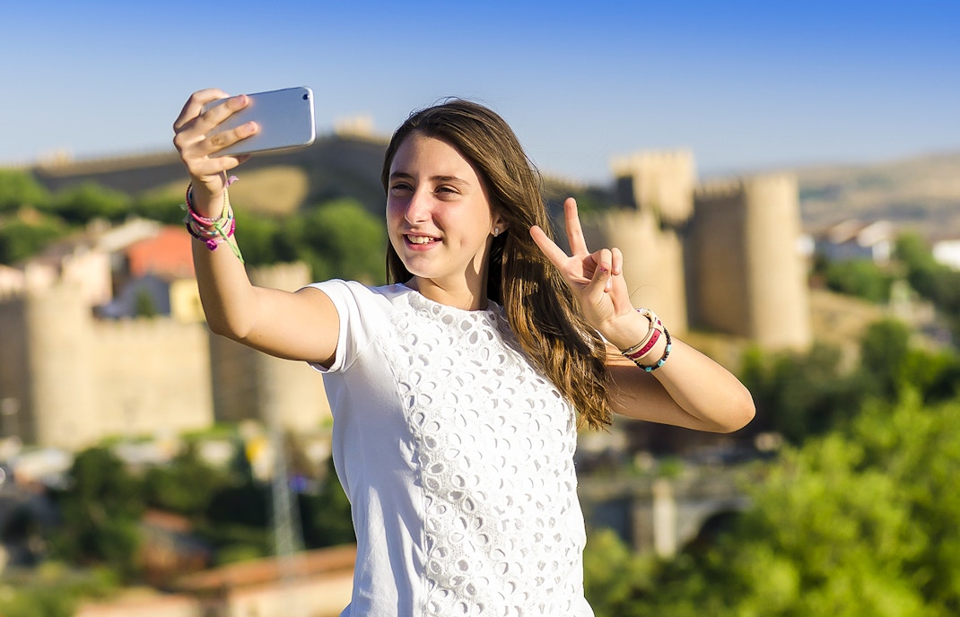 Person taking a selfie with Avila city walls in the background during Segovia & Avila day trip.