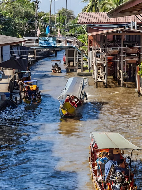 Boats navigating a bustling floating market canal with shops on both sides.
