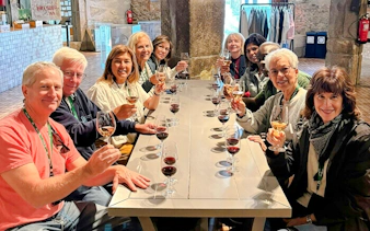 Guests seated at a long table enjoying a wine tasting experience indoors.
