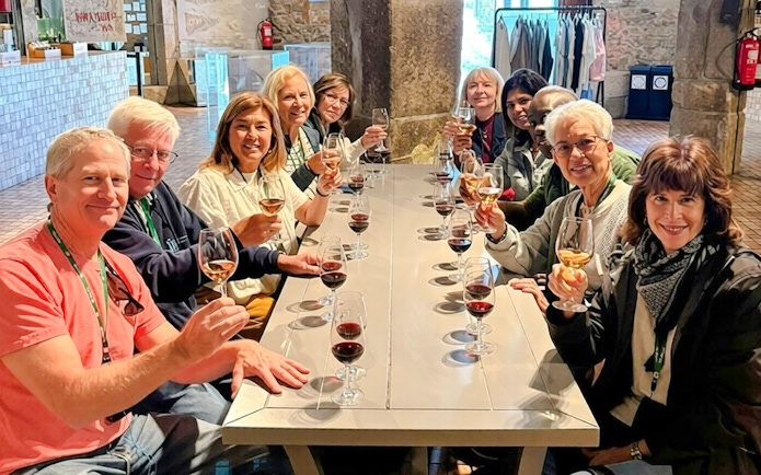 Guests seated at a long table enjoying a wine tasting experience indoors.